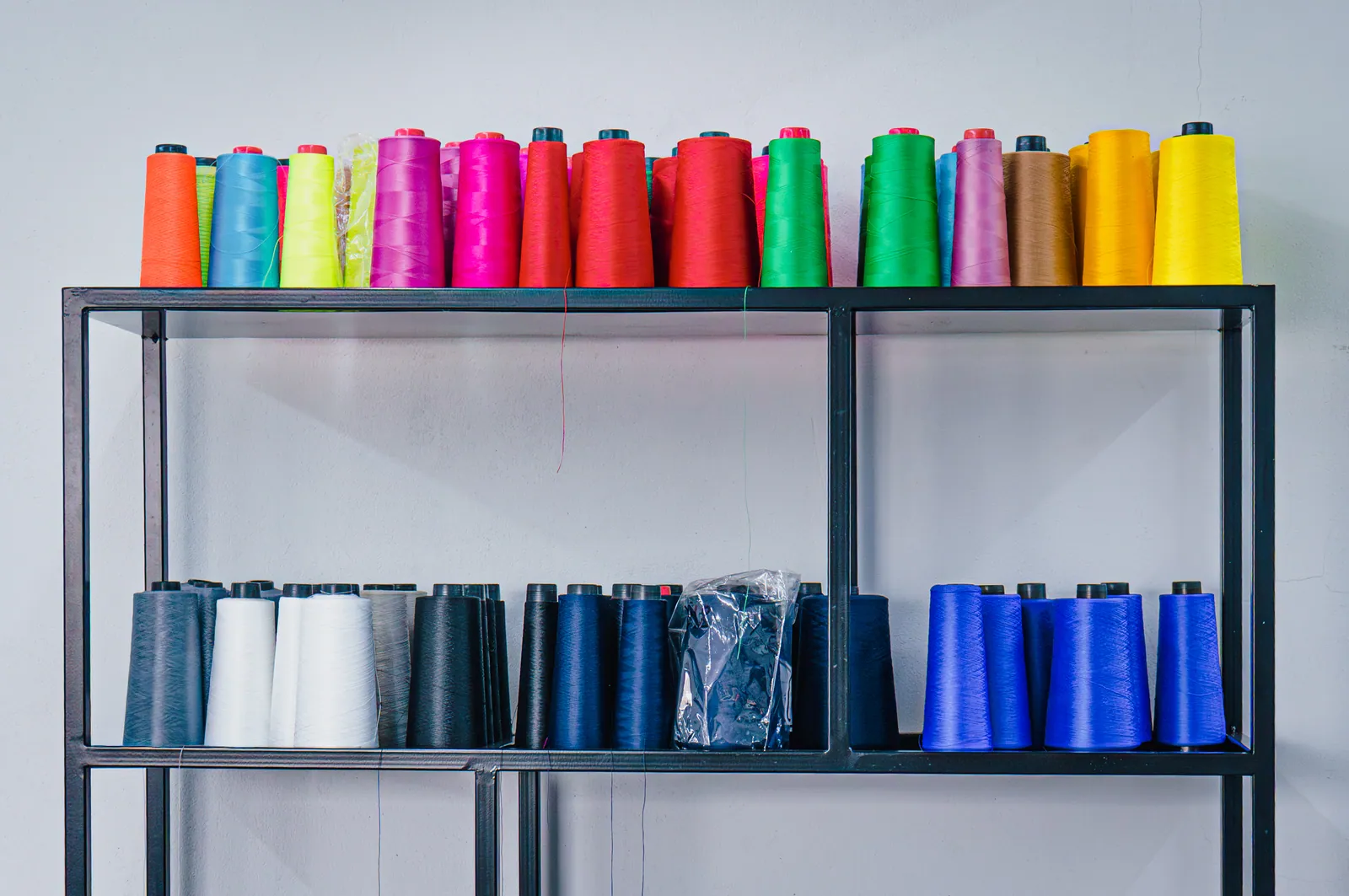 Estantería con conos de hilo de todos los colores en la fábrica de 30 Colores